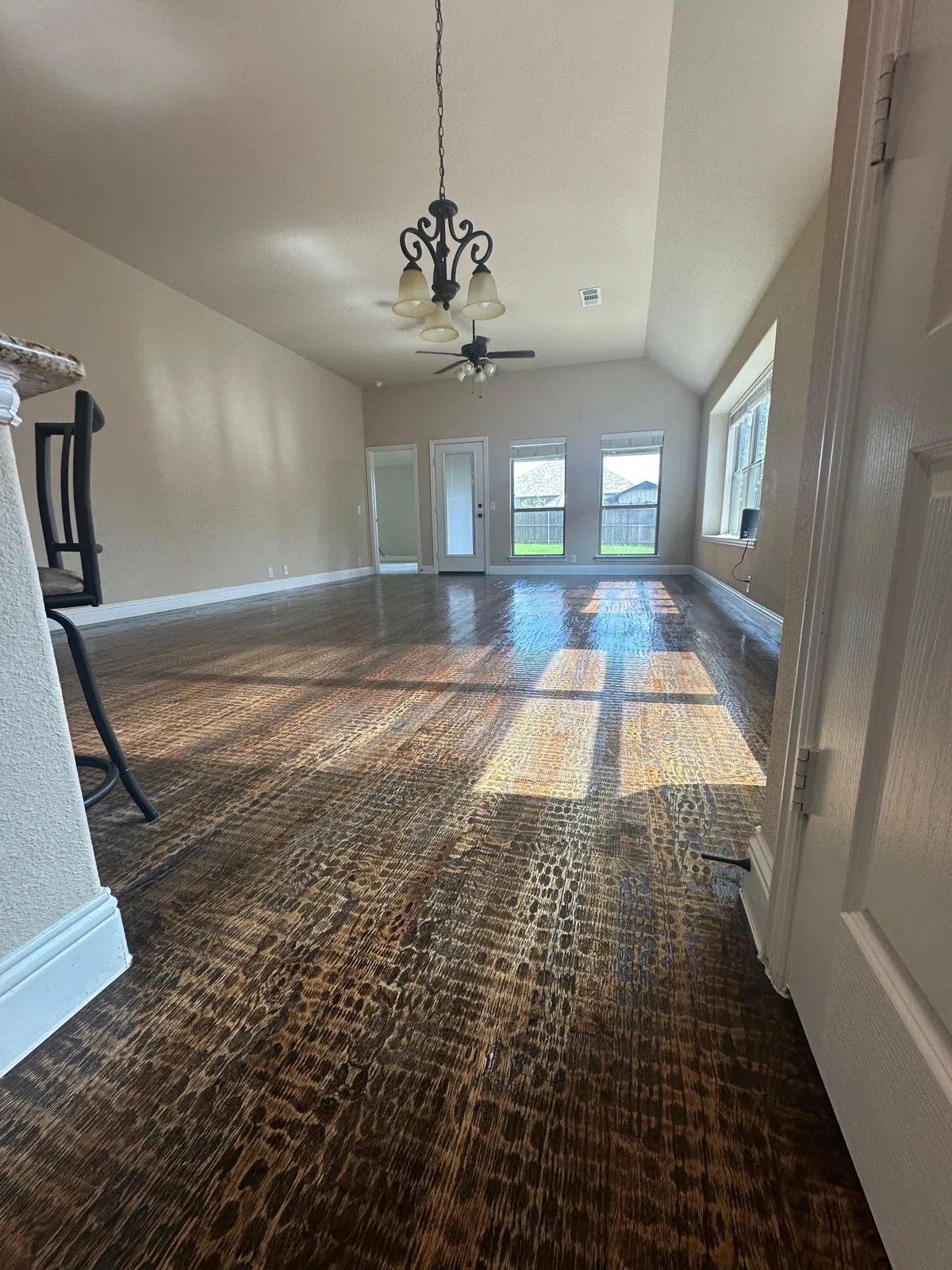 Empty living room with gleaming dark wood floor and chandelier after a Cleaning Echo move-out cleaning